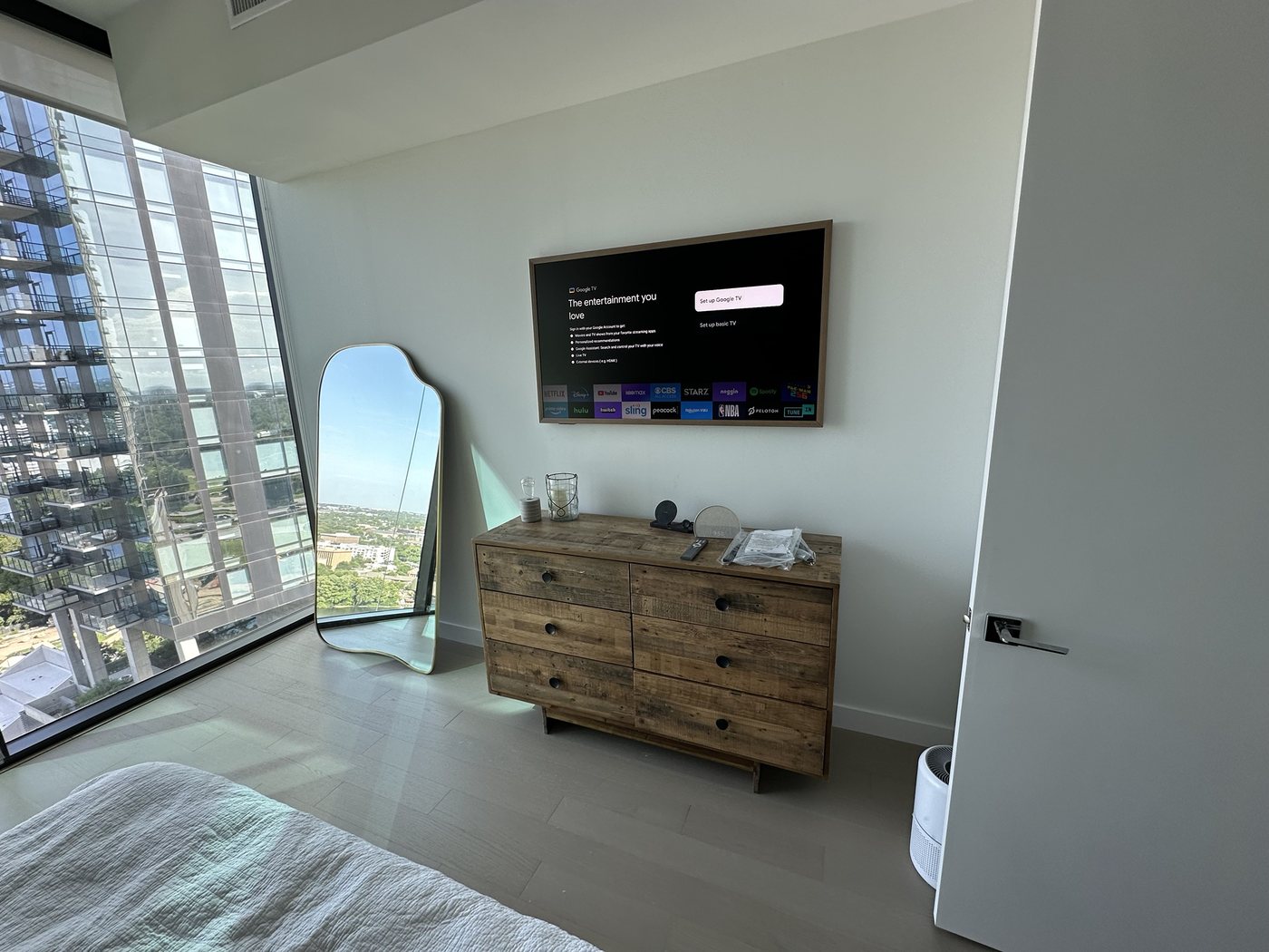Samsung Frame TV with a wood frame in a high-rise bedroom with floor-to-ceiling windows