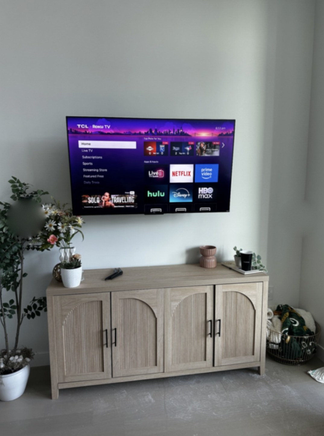 TCL TV mounted at eye level above an oak media console